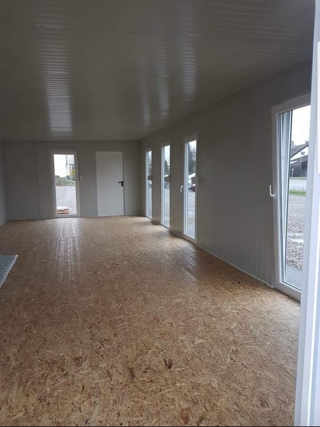 Innenraum eines von Frigano realisierten Bürocontainers mit großen Fenstern und OSB-Boden
